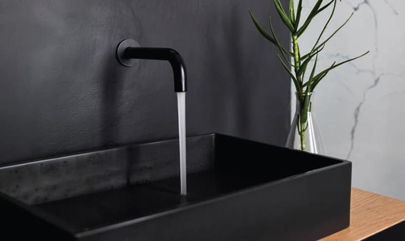 Black wall-mounted tap running into a matt black basin